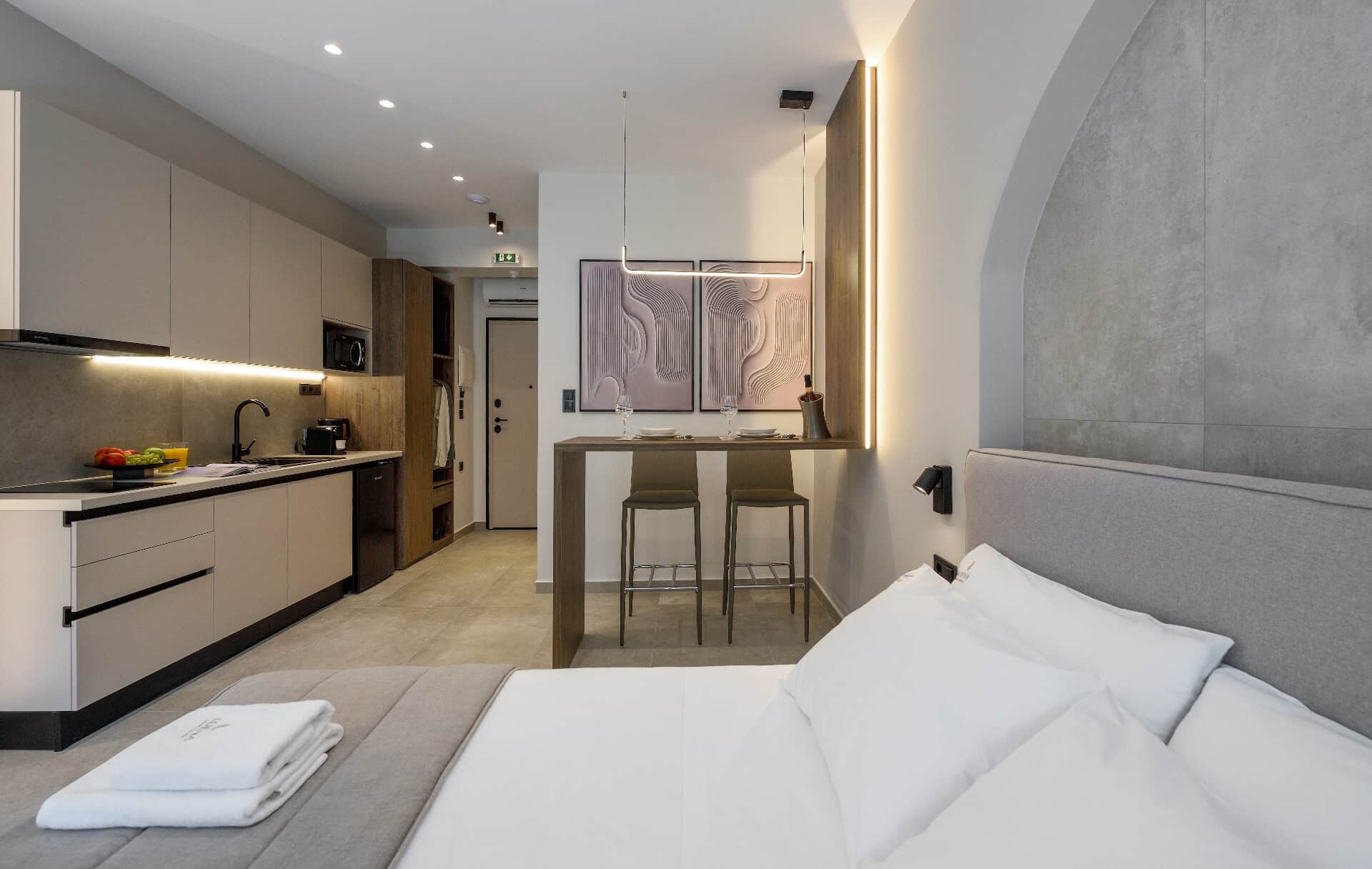 The whole suite in one frame: the kitchenette, the bar table, and the queen bed