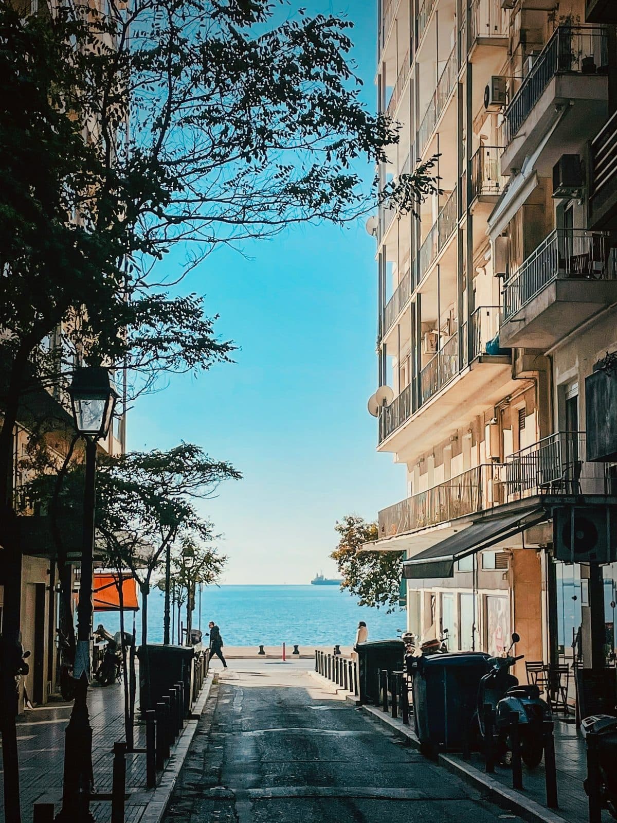 A Thessaloniki street running downhill between apartment blocks to the waterfront