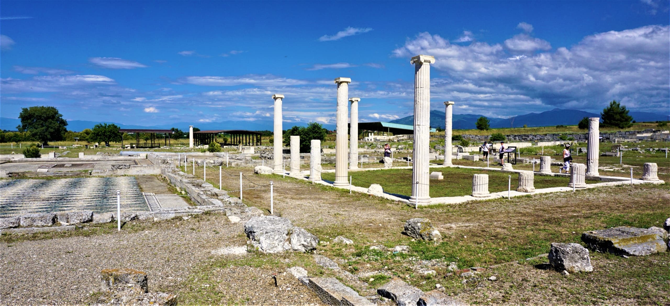 Restored Ionic columns and a mosaic floor at the archaeological site of Pella, mountains on the horizon.
